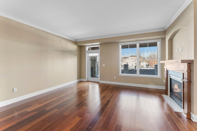 unfurnished living room with baseboards, a glass covered fireplace, crown molding, and dark wood-type flooring