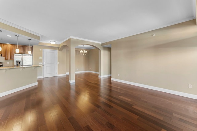 unfurnished living room featuring ornamental molding, baseboards, an inviting chandelier, arched walkways, and dark wood-type flooring