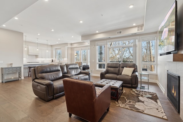 living area with baseboards, visible vents, dark wood finished floors, a fireplace, and recessed lighting