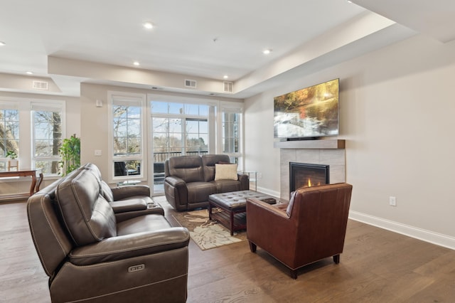 living area featuring baseboards, a fireplace, visible vents, and wood finished floors