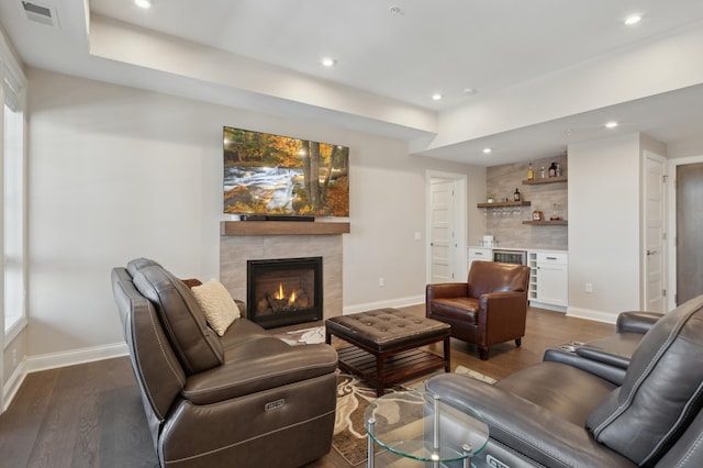 living room with a bar, dark wood-style flooring, a fireplace, and baseboards