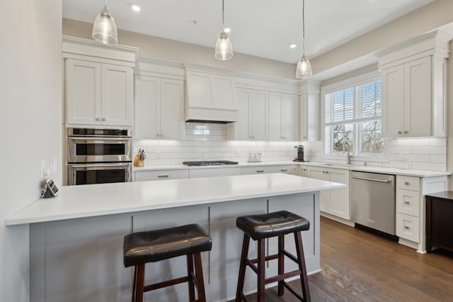 kitchen with stainless steel appliances, a sink, decorative backsplash, and a kitchen bar