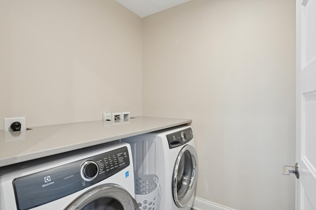 clothes washing area featuring baseboards, laundry area, and washer and dryer