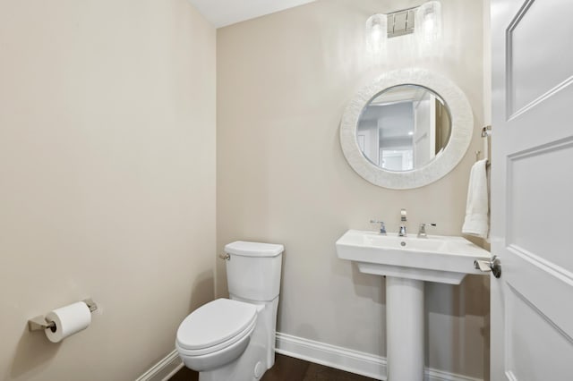 bathroom featuring a sink, toilet, and baseboards