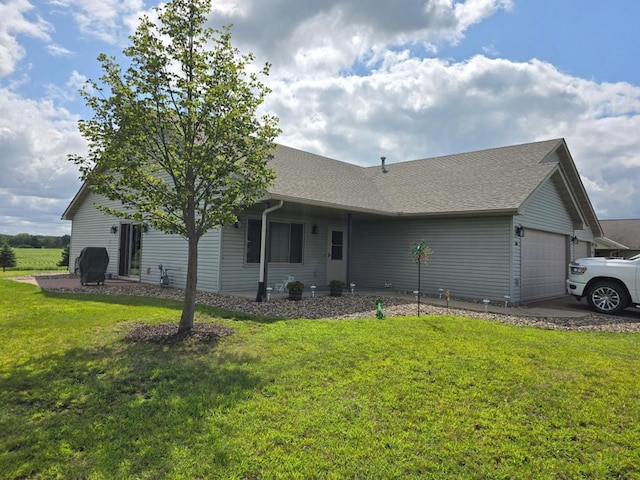 ranch-style home with a garage, roof with shingles, and a front yard