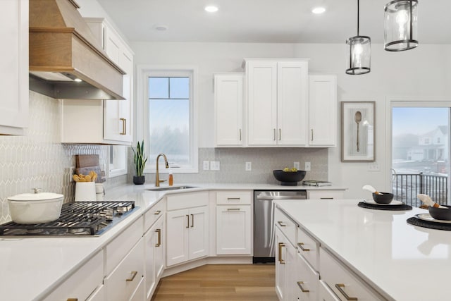 kitchen with premium range hood, a sink, white cabinetry, light countertops, and appliances with stainless steel finishes