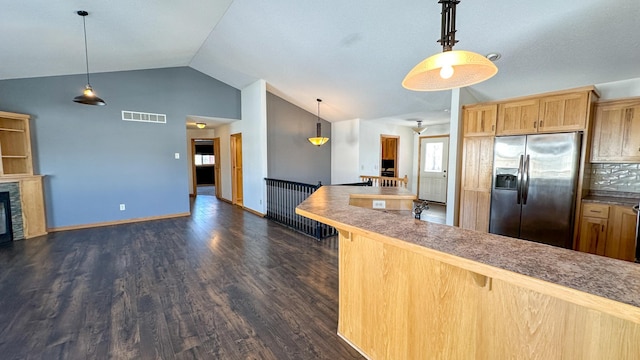 kitchen featuring dark hardwood / wood-style floors, stainless steel fridge, vaulted ceiling, a kitchen breakfast bar, and pendant lighting