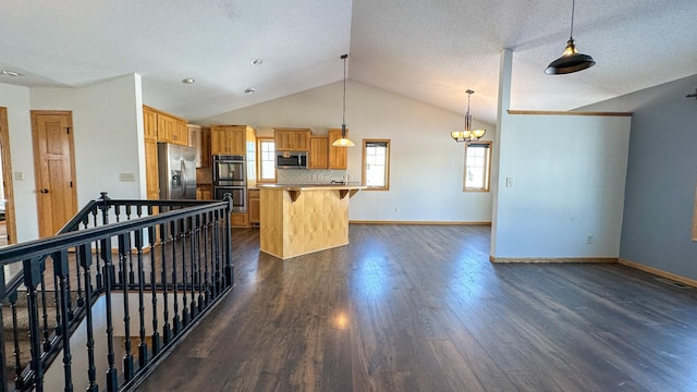 kitchen with appliances with stainless steel finishes, decorative light fixtures, a breakfast bar, a center island, and dark hardwood / wood-style flooring