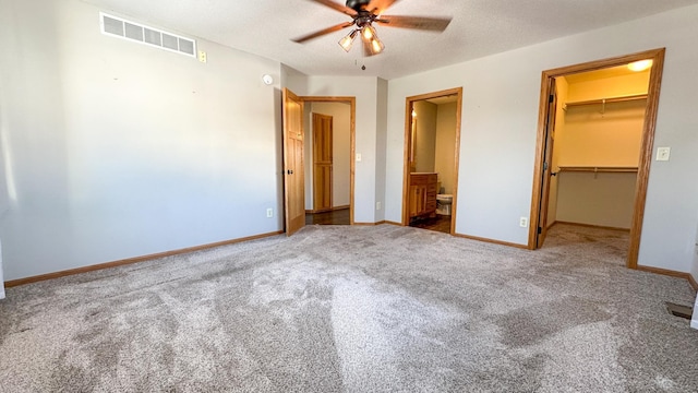 unfurnished bedroom with a closet, ensuite bath, carpet floors, a spacious closet, and a textured ceiling