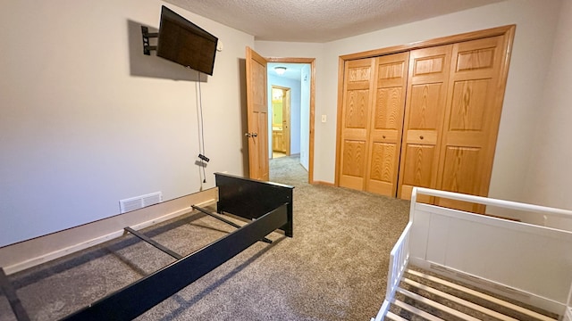 carpeted bedroom featuring a textured ceiling and a closet