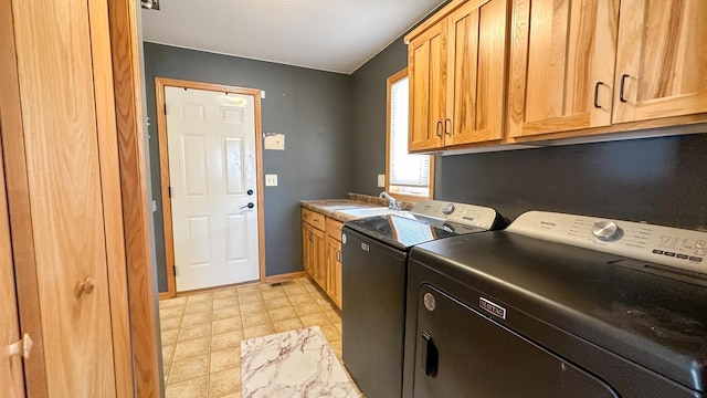 clothes washing area featuring cabinets, sink, and washing machine and clothes dryer