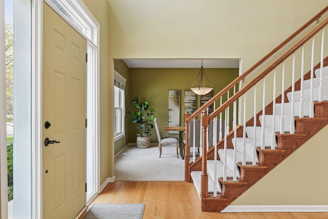 entrance foyer featuring stairs, baseboards, a wealth of natural light, and light wood-type flooring