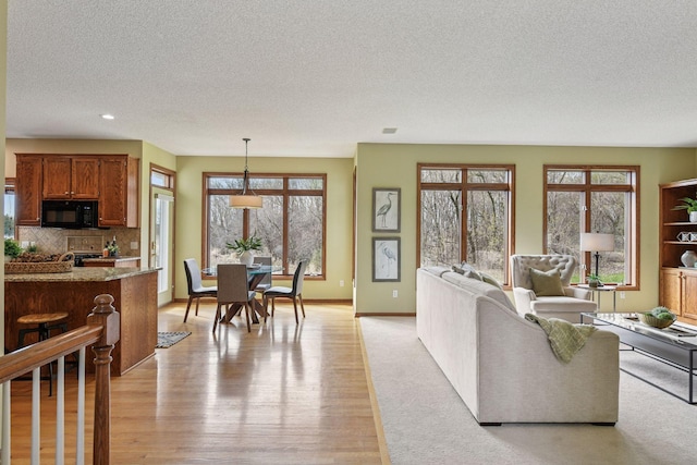 living room featuring light wood-style floors, recessed lighting, a textured ceiling, and baseboards