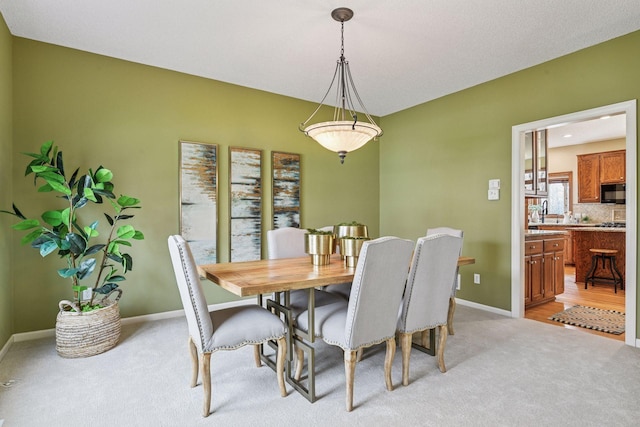 dining space with baseboards and light colored carpet