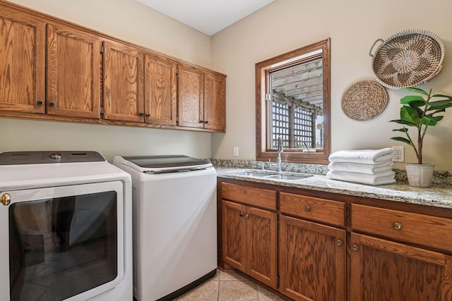 clothes washing area with washing machine and clothes dryer, light tile patterned floors, a sink, and cabinet space