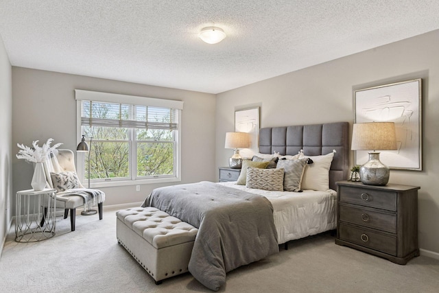 bedroom featuring light colored carpet, a textured ceiling, and baseboards