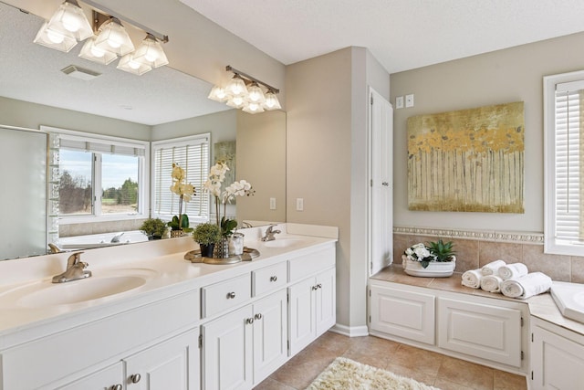 bathroom with visible vents, a sink, a bath, and double vanity