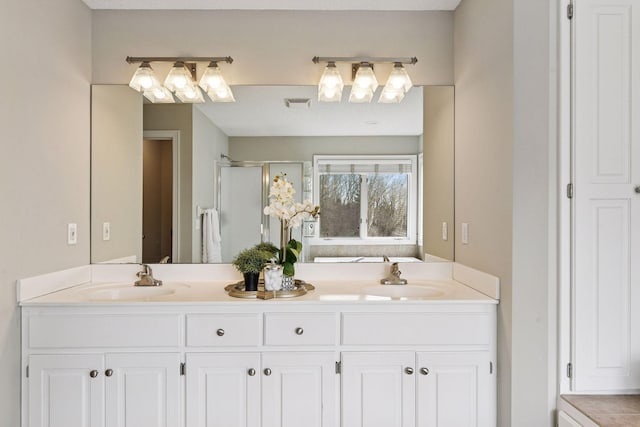 bathroom featuring visible vents, a sink, a stall shower, and double vanity
