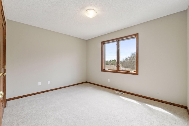 spare room featuring baseboards, light colored carpet, and visible vents