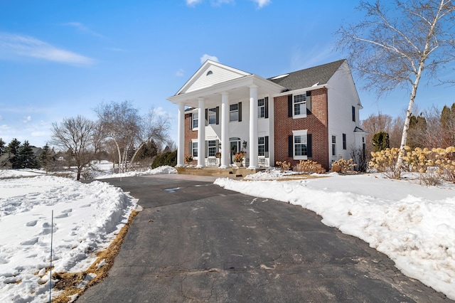 greek revival inspired property featuring brick siding and a porch