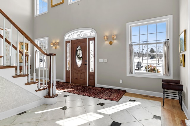 tiled foyer featuring visible vents, baseboards, and stairs