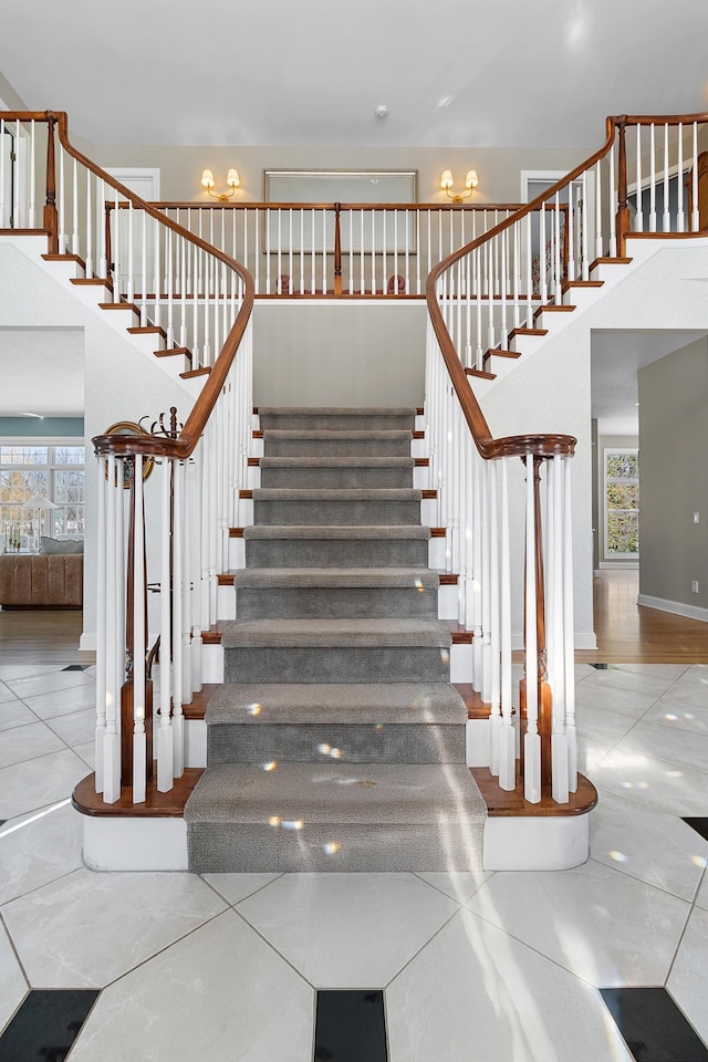 stairway featuring baseboards, a high ceiling, and tile patterned flooring