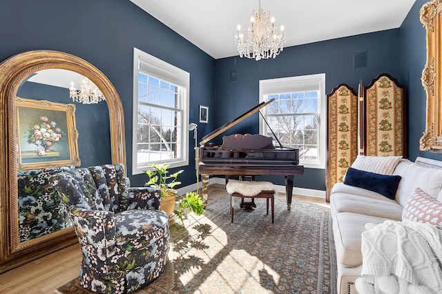 living area with a chandelier, visible vents, baseboards, and wood finished floors