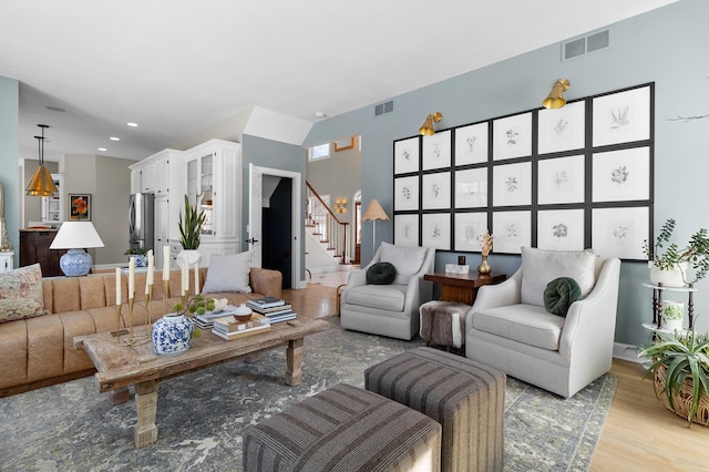 living area featuring recessed lighting, visible vents, light wood finished floors, and stairway