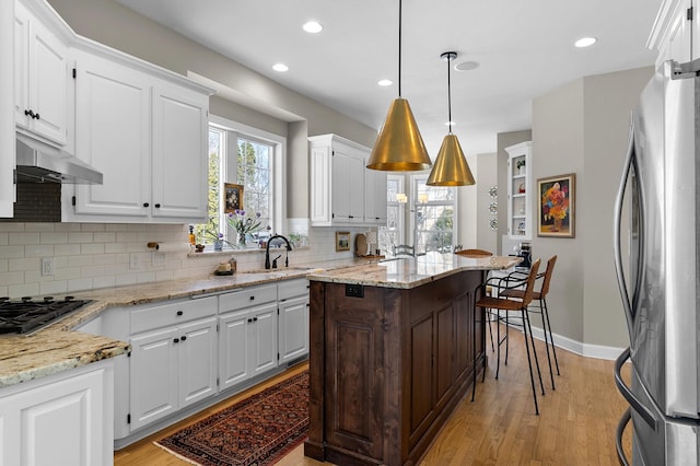 kitchen with a sink, white cabinets, under cabinet range hood, and stainless steel appliances