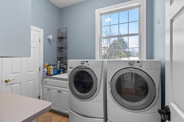 washroom featuring cabinet space, light tile patterned floors, and washing machine and dryer