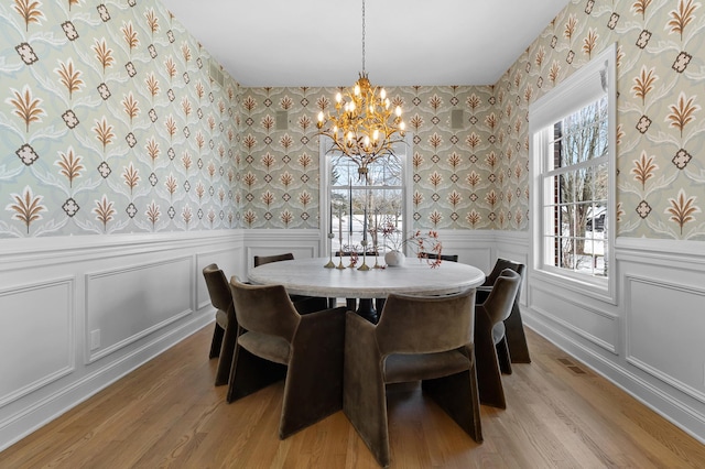 dining area featuring visible vents, wallpapered walls, a wainscoted wall, light wood-style floors, and a decorative wall