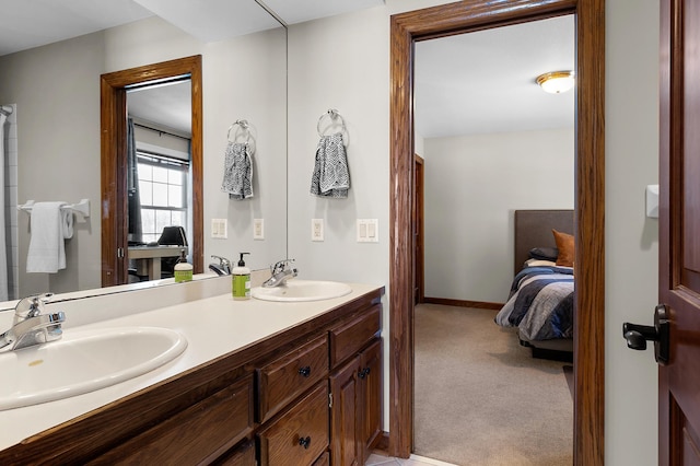 ensuite bathroom featuring a sink, baseboards, ensuite bath, and double vanity