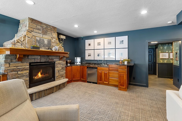 kitchen with brown cabinets, light carpet, a sink, a fireplace, and dishwasher