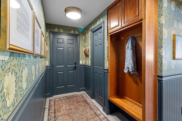 mudroom with tile patterned flooring, a wainscoted wall, and wallpapered walls