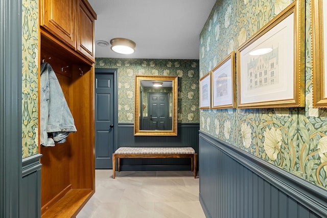 mudroom with wallpapered walls and wainscoting