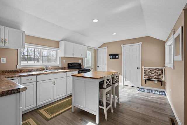 kitchen featuring white cabinets, a kitchen island, black electric range oven, vaulted ceiling, and wooden counters