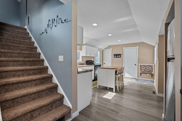 staircase with vaulted ceiling, recessed lighting, wood finished floors, and baseboards