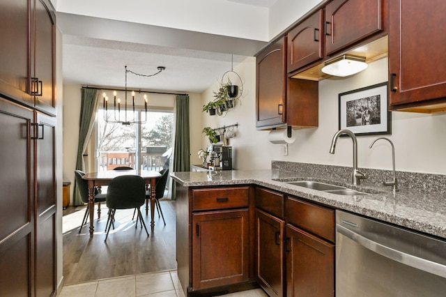 kitchen with light stone counters, hanging light fixtures, a peninsula, stainless steel dishwasher, and a sink