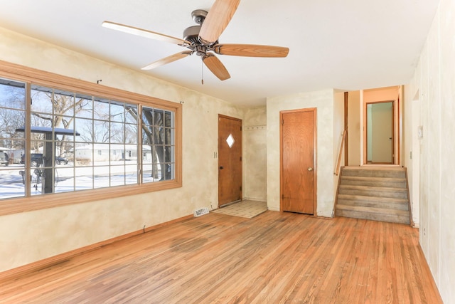 empty room featuring a healthy amount of sunlight, ceiling fan, and light hardwood / wood-style floors