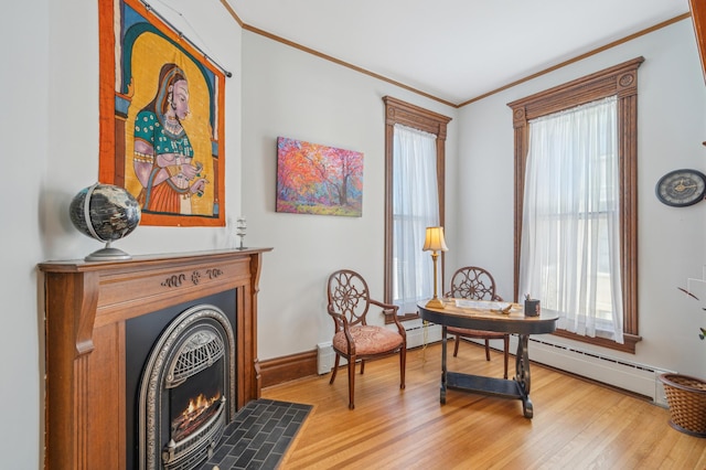 sitting room with baseboard heating, wood-type flooring, and ornamental molding