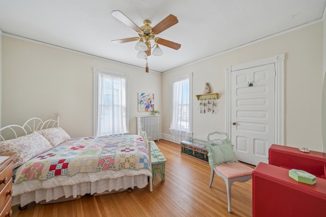 bedroom with crown molding, wood-type flooring, and ceiling fan