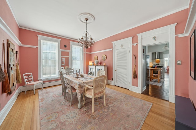 dining room with baseboard heating, light hardwood / wood-style floors, a chandelier, and crown molding