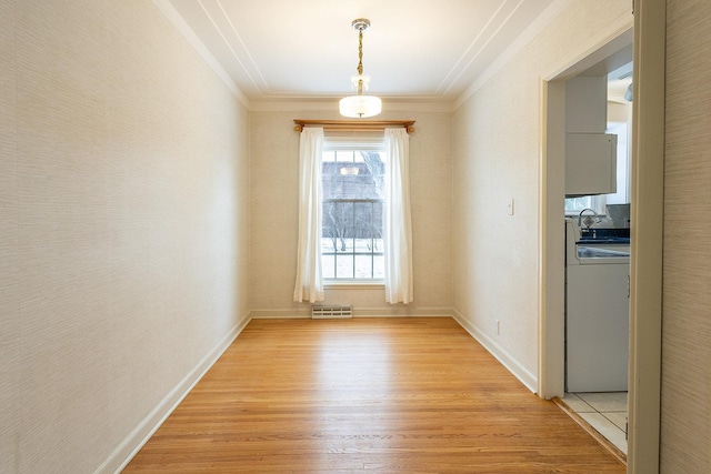 unfurnished dining area with light wood finished floors, visible vents, baseboards, washer / clothes dryer, and crown molding