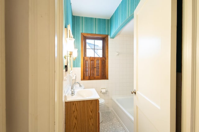 bathroom with tile walls, wallpapered walls, toilet, vanity, and tile patterned floors