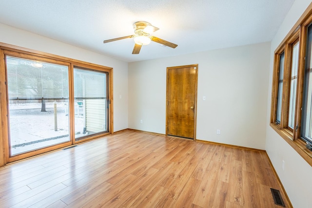 unfurnished room with a ceiling fan, light wood-style flooring, visible vents, and baseboards