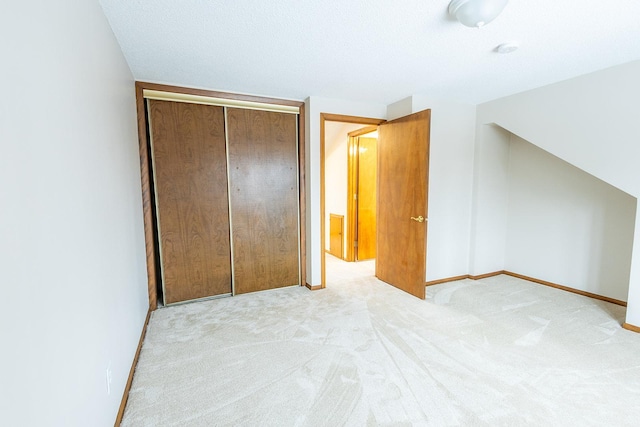 unfurnished bedroom with vaulted ceiling, a closet, carpet, and baseboards