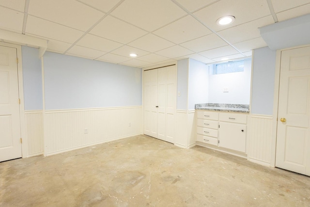 basement featuring recessed lighting, wainscoting, and a drop ceiling