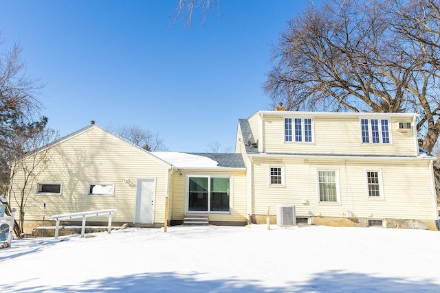 snow covered property featuring entry steps, a chimney, and cooling unit