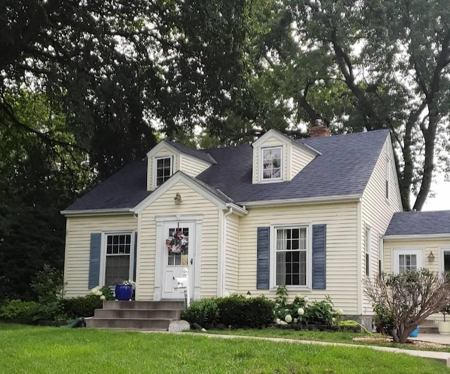 new england style home with a front lawn and roof with shingles