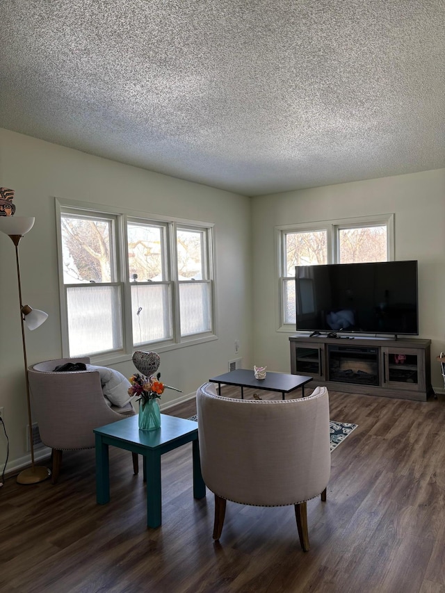 living room featuring a textured ceiling, dark wood finished floors, and baseboards